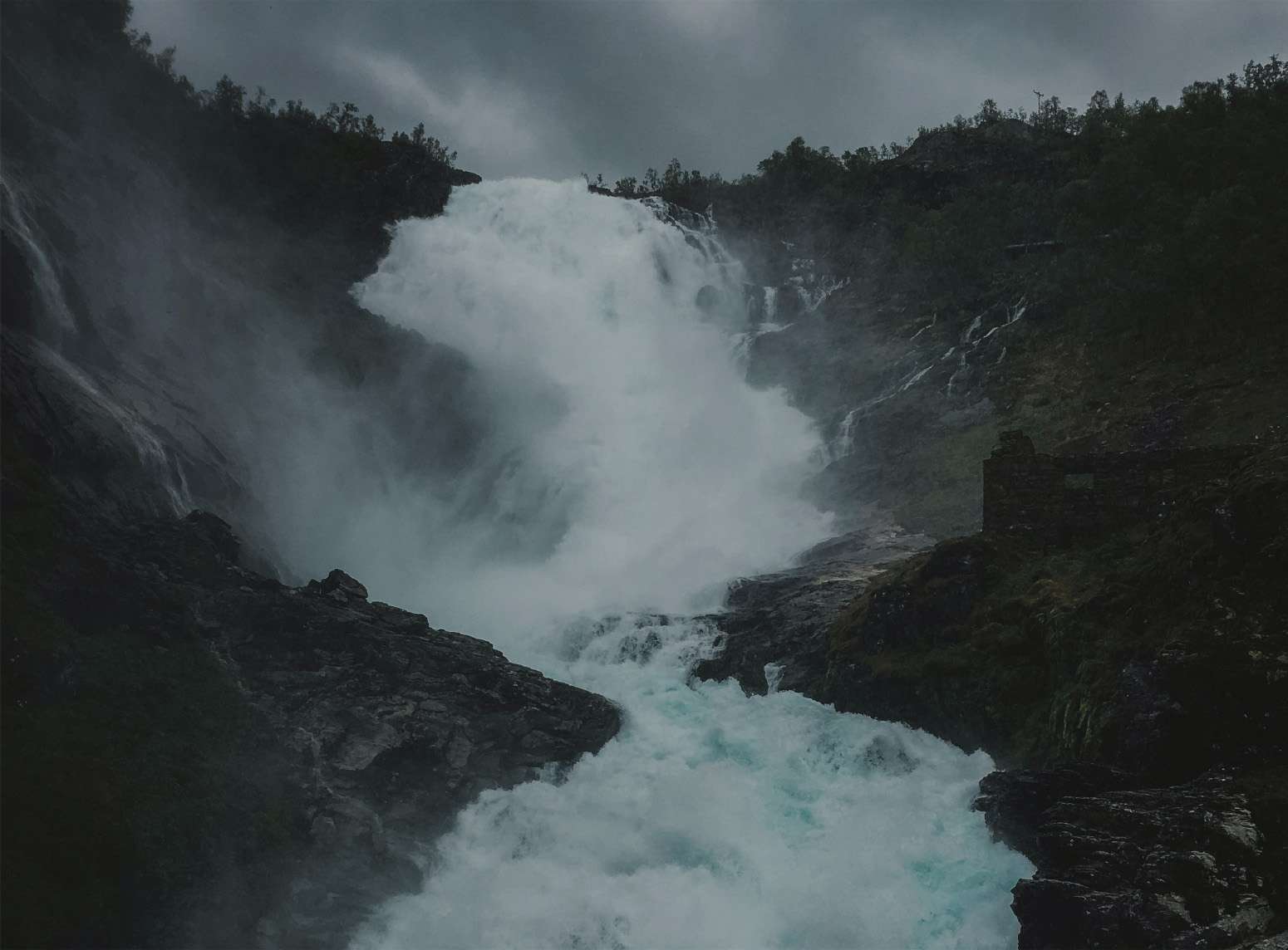 Imagen de una enorme cascada por donde el agua corre con una gran fuerza, arrasando aquello por lo que pasa.